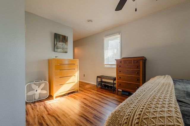 bedroom with ceiling fan, wood finished floors, and baseboards