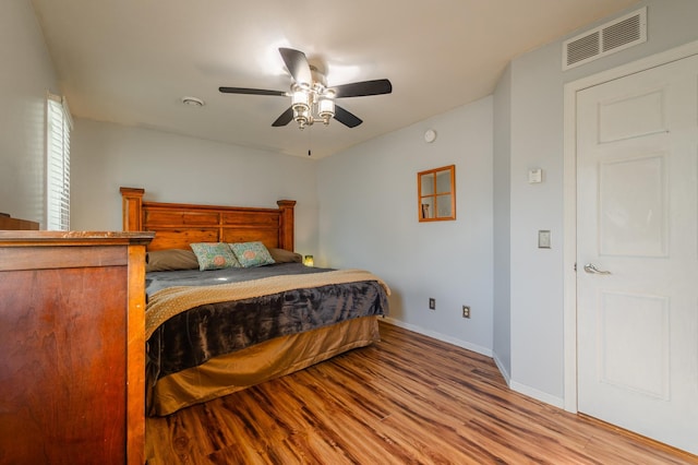 bedroom with a ceiling fan, baseboards, visible vents, and wood finished floors