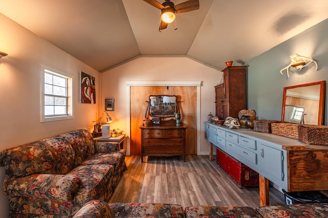 living area with a ceiling fan, vaulted ceiling, and wood finished floors