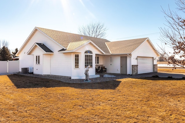 single story home with a garage, roof with shingles, fence, a front lawn, and central AC