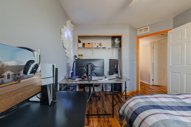 bedroom with baseboards, visible vents, and wood finished floors