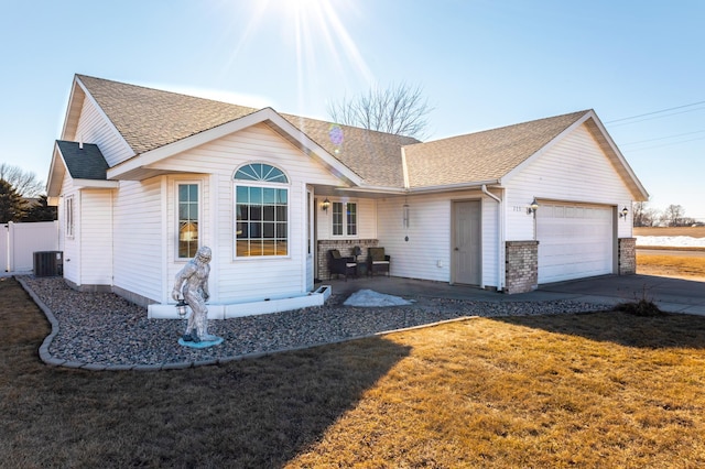 ranch-style home featuring a garage, central AC, a shingled roof, concrete driveway, and a front lawn