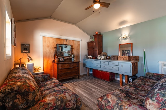 living area featuring lofted ceiling, wood finished floors, and a ceiling fan