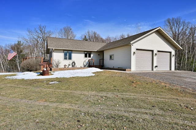 single story home featuring a front lawn, gravel driveway, and an attached garage