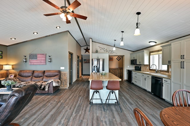 kitchen with a breakfast bar area, ornamental molding, open floor plan, a sink, and black appliances