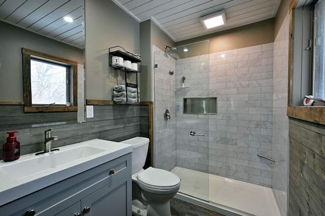 bathroom featuring toilet, tile walls, tiled shower, and vanity