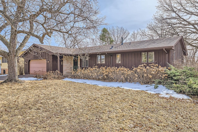 ranch-style home with brick siding, board and batten siding, a shingled roof, and a garage