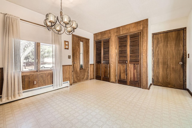 unfurnished dining area with tile patterned floors, baseboard heating, a wainscoted wall, and wood walls