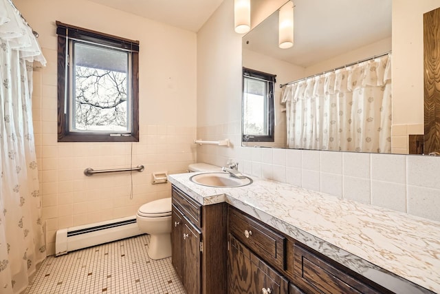 bathroom with tile patterned flooring, toilet, vanity, baseboard heating, and tile walls