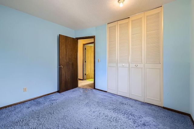 unfurnished bedroom with a textured ceiling, carpet, a closet, and baseboards