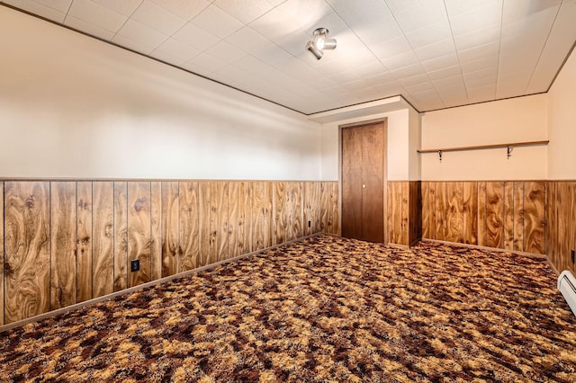 carpeted spare room with wooden walls and a wainscoted wall