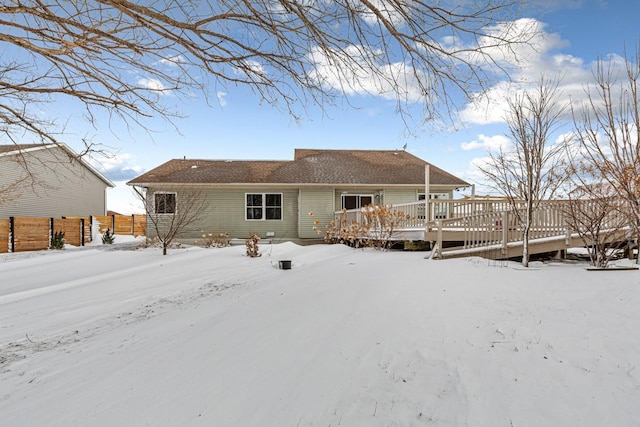 snow covered house featuring fence and a wooden deck