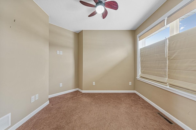 carpeted empty room featuring baseboards, visible vents, and ceiling fan