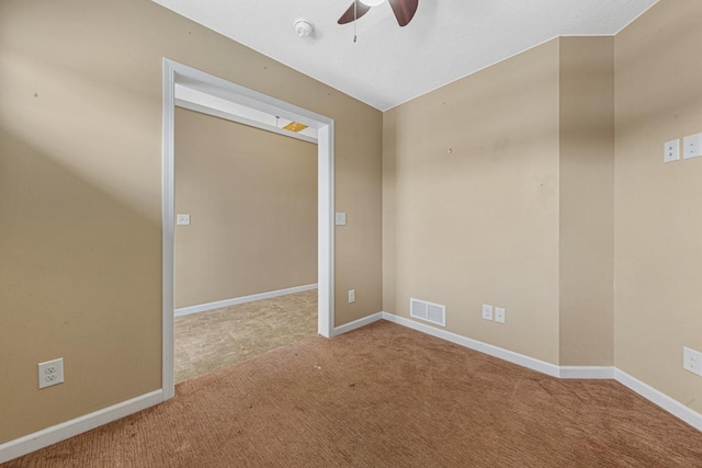 carpeted spare room featuring a ceiling fan, visible vents, and baseboards