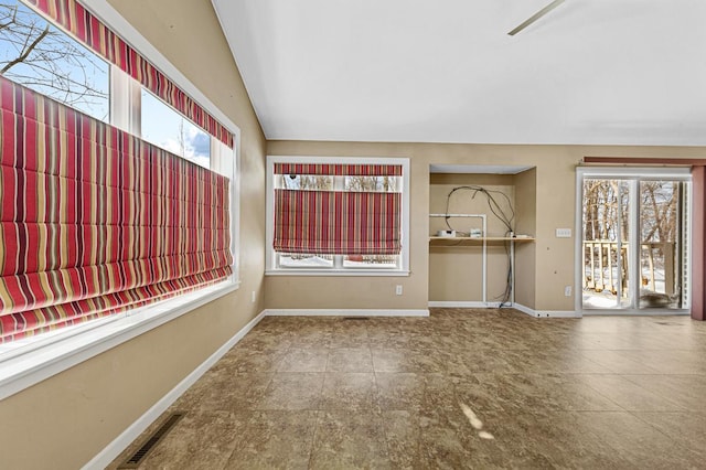 unfurnished room with lofted ceiling, visible vents, and baseboards