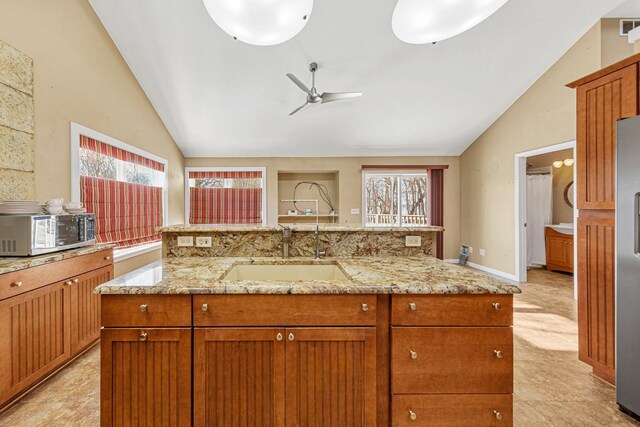 kitchen with a ceiling fan, lofted ceiling, a kitchen island with sink, stainless steel appliances, and a sink