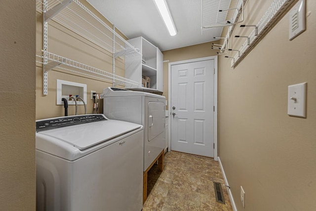 laundry room featuring laundry area, visible vents, baseboards, washer and dryer, and stone finish floor