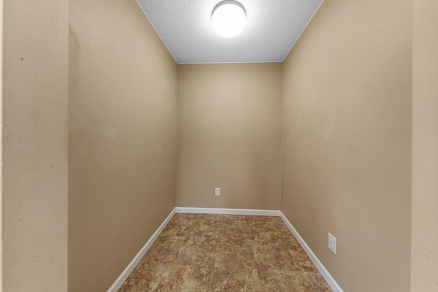 interior space with a textured ceiling and baseboards