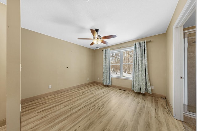 spare room with ceiling fan, light wood-type flooring, and baseboards