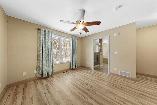 empty room featuring a ceiling fan, visible vents, baseboards, and wood finished floors