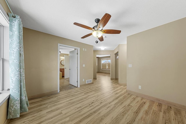 interior space featuring light wood-type flooring, baseboards, visible vents, and ceiling fan