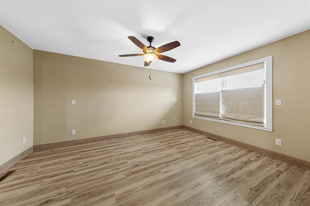 empty room with light wood finished floors, a ceiling fan, and baseboards