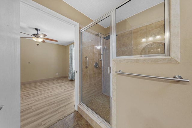 full bath with a ceiling fan, a stall shower, baseboards, and wood finished floors