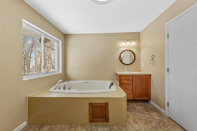 full bath with vanity, baseboards, and a bath