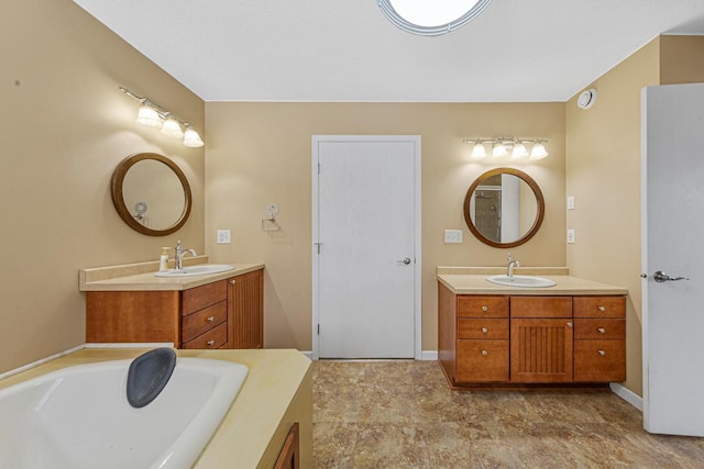 bathroom featuring a bath, two vanities, and a sink