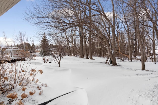 yard covered in snow featuring a garage and a deck