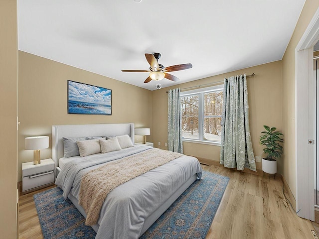 bedroom with light wood-style floors, ceiling fan, and baseboards