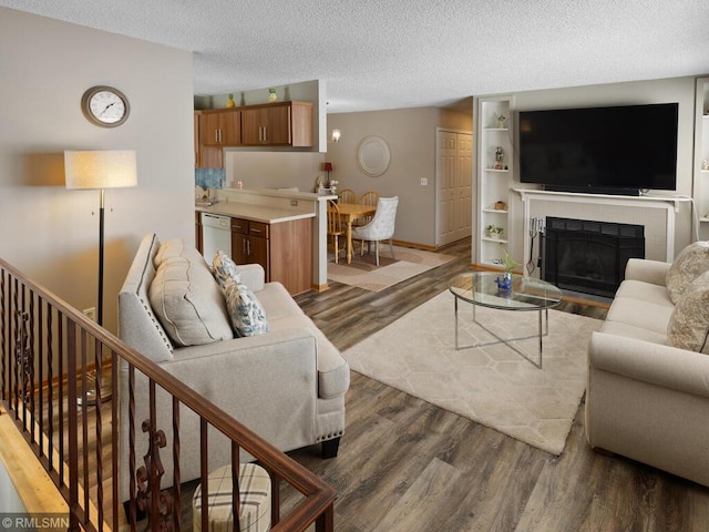 living room featuring a textured ceiling, baseboards, a fireplace, and wood finished floors