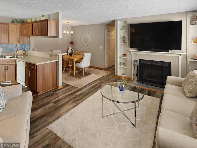 living area featuring a textured ceiling, a notable chandelier, a fireplace with flush hearth, baseboards, and dark wood-style floors