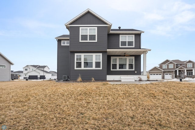 rear view of property featuring a ceiling fan and a lawn