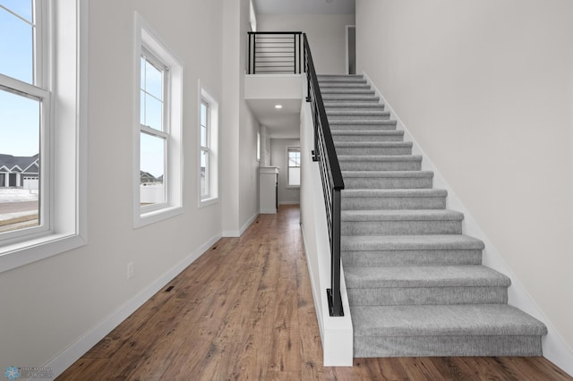 foyer entrance with stairs, a high ceiling, baseboards, and wood finished floors