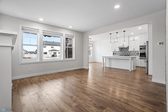 unfurnished living room with dark wood-style floors, baseboards, and recessed lighting