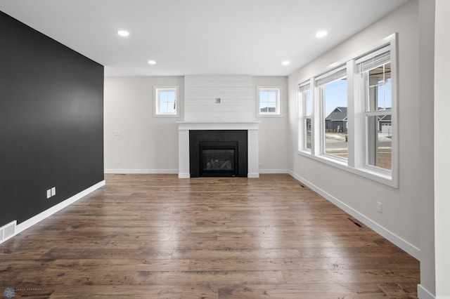 unfurnished living room with recessed lighting, a large fireplace, baseboards, and wood finished floors