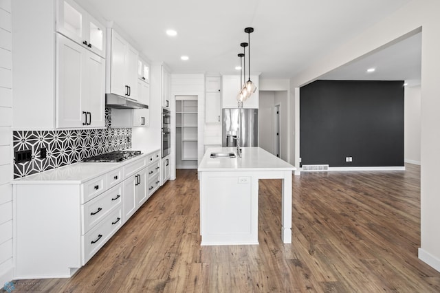 kitchen featuring visible vents, glass insert cabinets, wood finished floors, stainless steel appliances, and under cabinet range hood