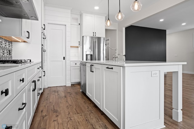 kitchen featuring light countertops, appliances with stainless steel finishes, dark wood-type flooring, and range hood