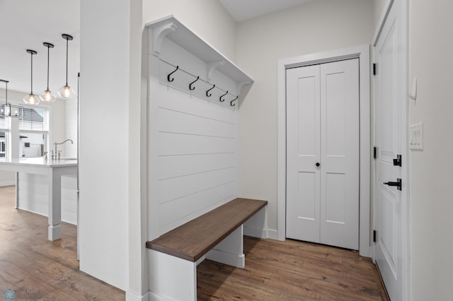 mudroom featuring a notable chandelier, a sink, and wood finished floors