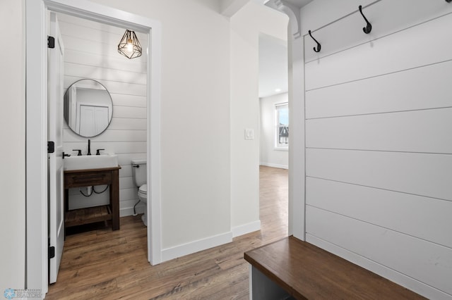 mudroom with baseboards, a sink, and wood finished floors