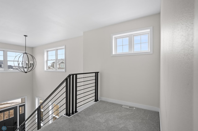 staircase featuring carpet flooring, a notable chandelier, and baseboards