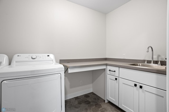 laundry area with washing machine and clothes dryer, cabinet space, a sink, dark tile patterned flooring, and baseboards