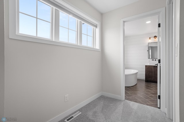 bathroom featuring a soaking tub, baseboards, visible vents, and vanity