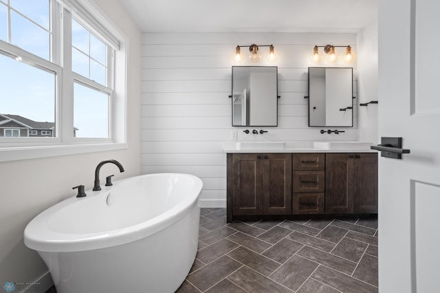 bathroom with a soaking tub, a sink, and double vanity