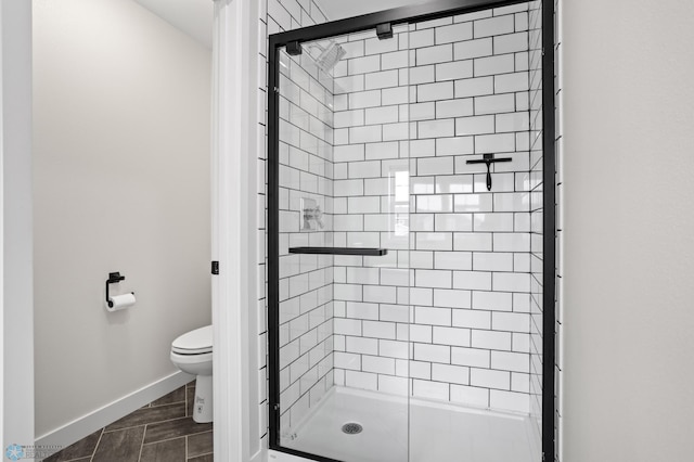 bathroom featuring baseboards, a shower stall, and toilet