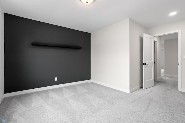 spare room with recessed lighting, light colored carpet, and baseboards