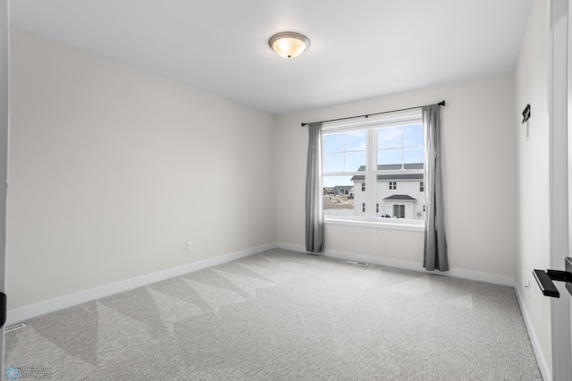 empty room featuring light carpet and baseboards