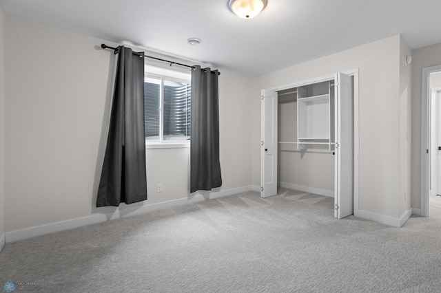 unfurnished bedroom with a closet, light carpet, and baseboards