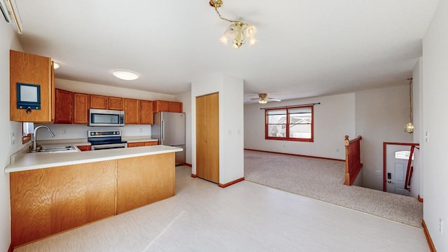 kitchen featuring a sink, appliances with stainless steel finishes, open floor plan, and light countertops